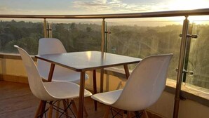 A balcony with a table and chairs, offering a view of the landscape. - Stay.Plus Nova Apartment Westlands (Nairobi)