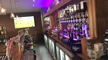 A bar area with a long counter, multiple taps, and a variety of liquor bottles.