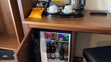 Een kleine keuken met een koelkast, een koffiezetapparaat en een waterkoker.