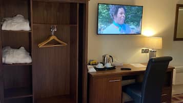 Ein Hotelzimmer mit einem Bett, einem Schreibtisch mit Stuhl, einem Fernseher, einem Kleiderschrank und einem roten Teppich.
