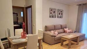 Ein modernes Wohnzimmer mit einer Couch, zwei Couchtischen und einem Essbereich mit Stühlen und einem Tisch.