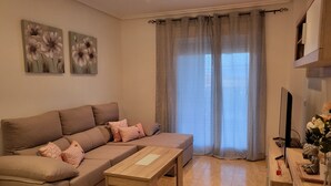 Ein Wohnzimmer mit einem braunen Sofa, einem Holztisch und einem Fernseher auf einem Holzschrank.