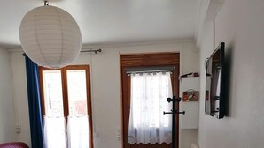 Una sala de estar con dos sofás de cuero rojo, una mesa blanca y un gran farol de papel blanco colgando del techo.