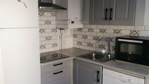 Una cocina con armarios blancos, un lavavajillas Bosch, un microondas y un lavabo.