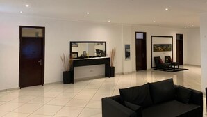 Un moderno vestíbulo de hotel con un mostrador de recepción, un sofá negro y un cuadro en la pared.