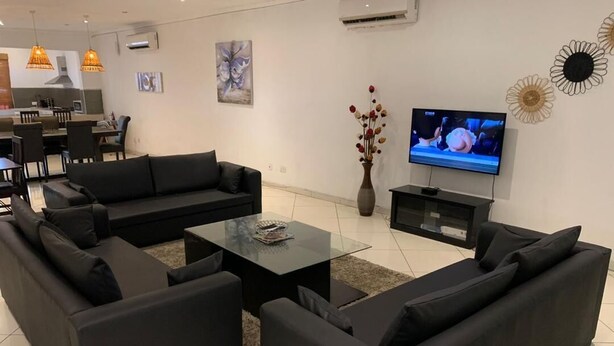 Una sala de estar moderna con un sofá seccional, una mesa de centro de vidrio y un televisor de pantalla plana.
