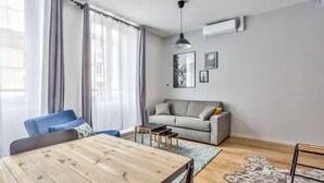 A modern living room with a wooden coffee table, grey sofa, and blue armchair.