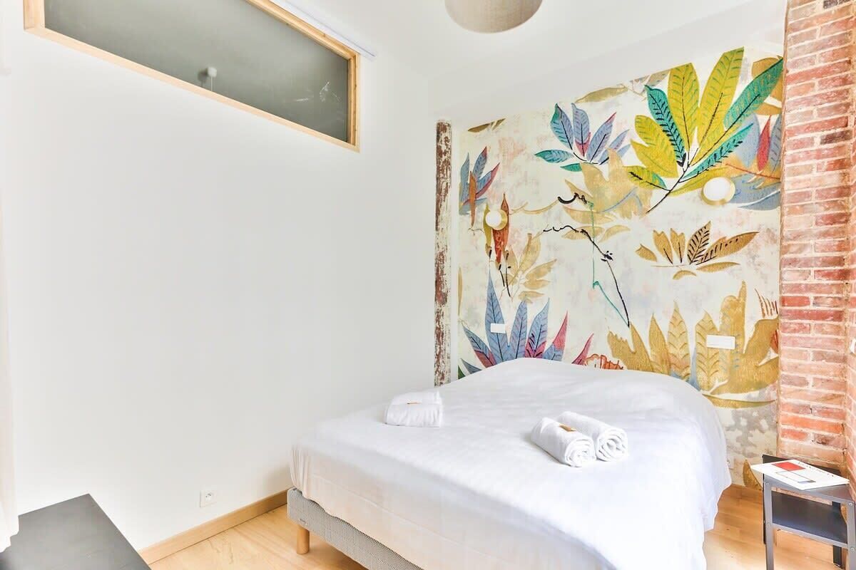 Une chambre à coucher avec un lit, une fenêtre, un mur en briques et une fresque murale.