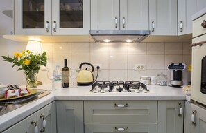 Una cocina moderna con estufa a gas, hervidor, máquina de café y un florero con flores en la encimera.