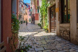 A narrow cobblestone street flanked by buildings with balconies, some with laundry hanging out to dry. - Romantic studio Yellow Flower in old town Rovinj near sea with private parking (Rovinj)