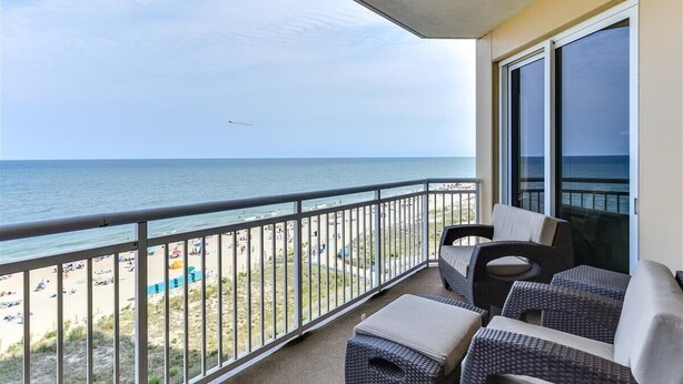 Un balcone con mobili in vimini che si affaccia su una spiaggia.