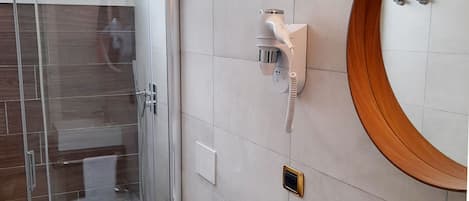 Un baño moderno con cabina de ducha de vidrio, inodoro, lavabo y tocador con espejo.