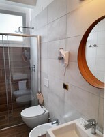 Un baño moderno con cabina de ducha de vidrio, inodoro, lavabo y tocador con espejo.