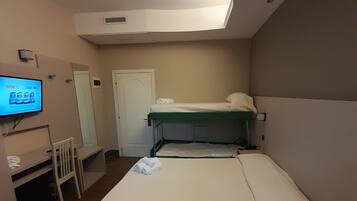 Habitació d'hotel amb un llit, escriptori, cadira, televisió i llum al sostre.