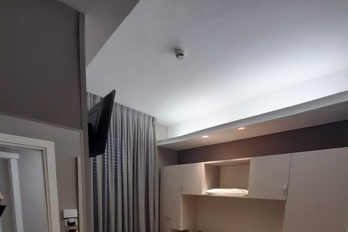 Ett modernt hotellrum med en stor säng, inbyggd garderob och en platt-TV.