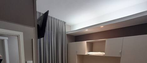 A modern hotel room with a large bed, built-in wardrobe, and a flat-screen TV.
