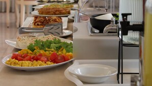 A buffet setup with various dishes, including salads, vegetables, and a beverage station. - Hotel Royal Plaza (Rimini)