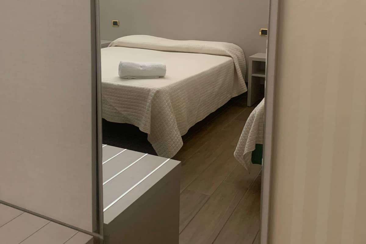 Ett hotellrum med en säng, ett sängbord och en spegel.