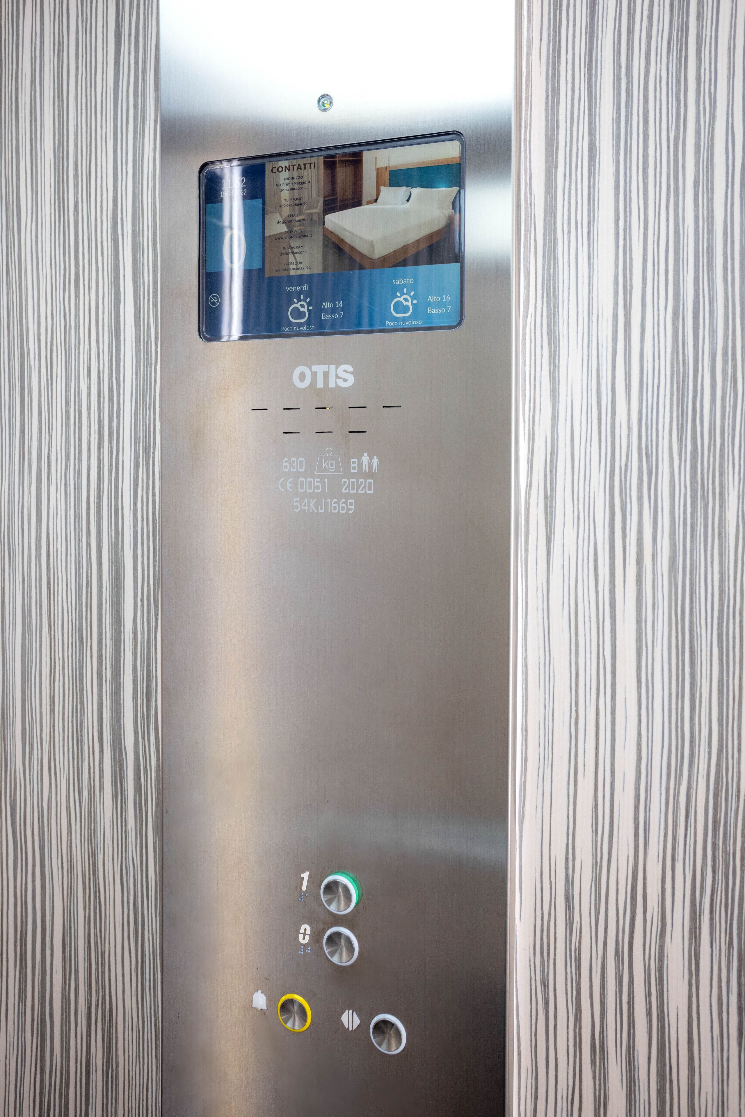 An elevator control panel with a digital display, buttons for floor selection, and a weight limit indicator.