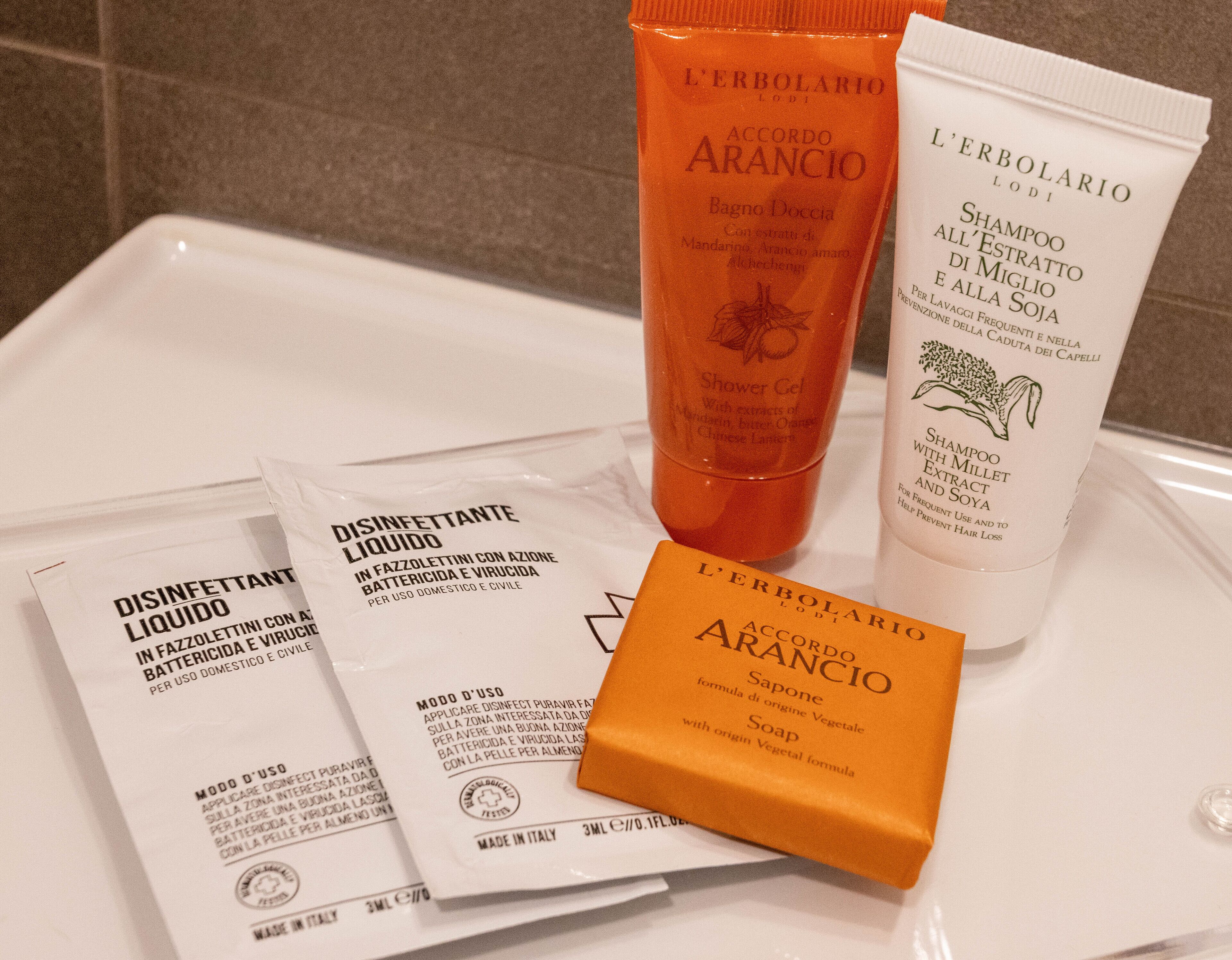 Toiletries including a shower gel, shampoo, and soap on a bathroom counter.