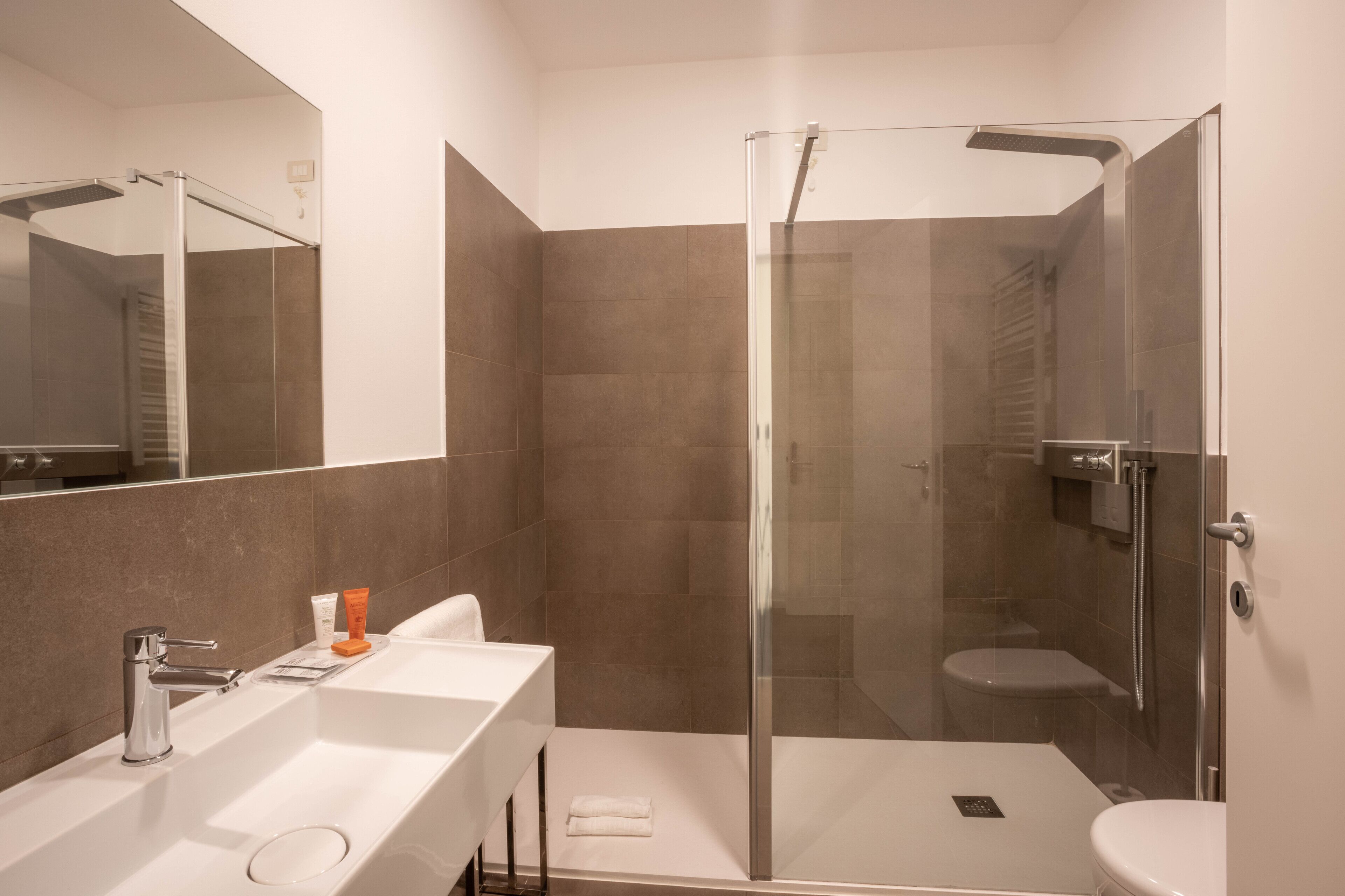 A modern bathroom with a glass-enclosed shower, a white sink, and a toilet.