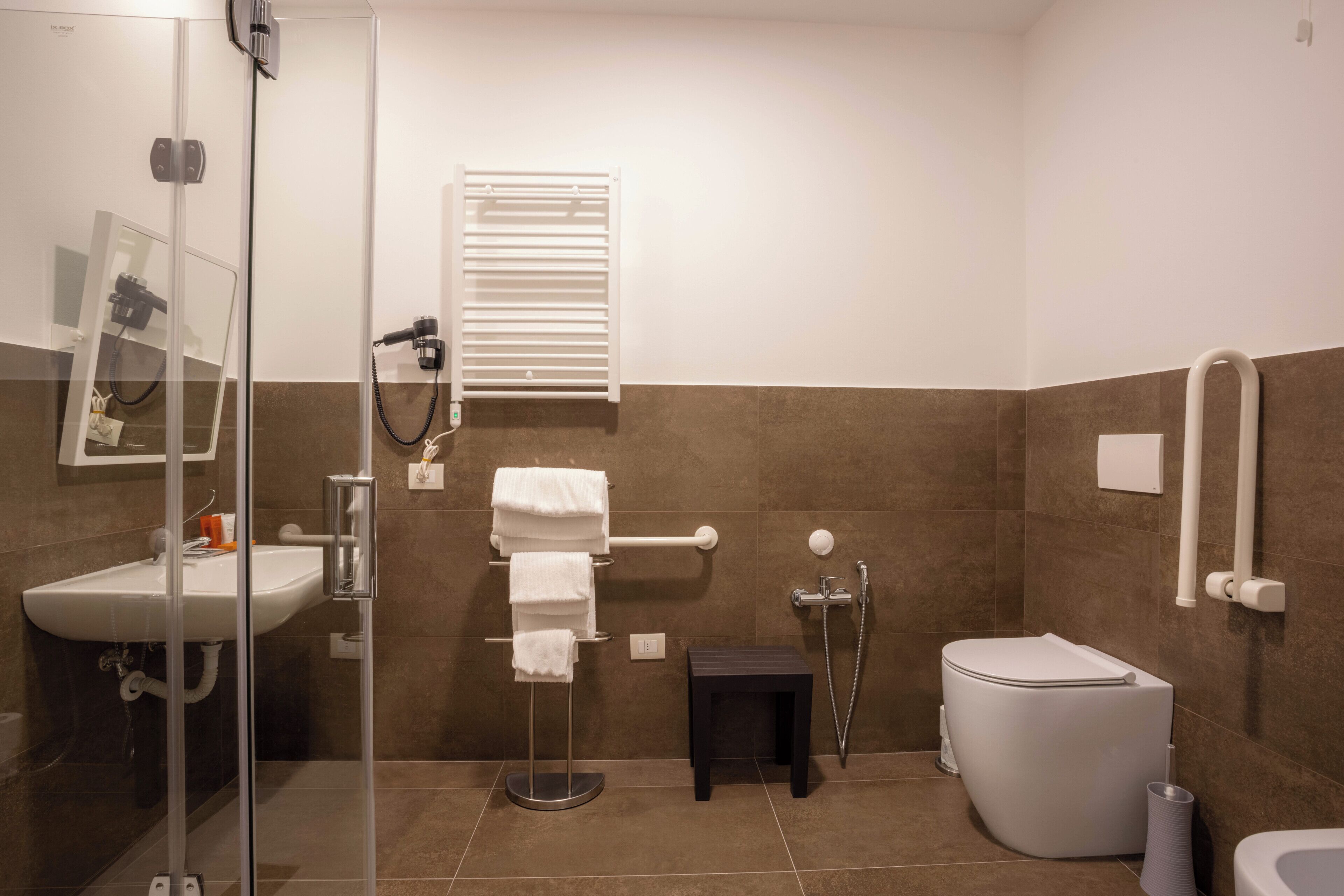 A modern bathroom with a glass shower enclosure, a white sink, a toilet, and a towel rack.