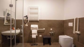 Un bagno moderno con cabina doccia in vetro, lavabo bianco, water e porta asciugamani.
