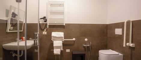 A modern bathroom with a glass shower enclosure, a white sink, a toilet, and a towel rack.