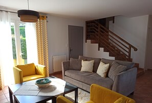 A living room with a sofa, yellow armchairs, a coffee table, and a staircase.