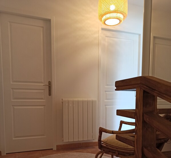 En hall med en trästol, en vit dörr och ett element.