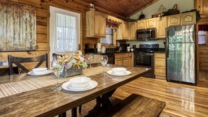 Une cuisine aménagée dans le style d’un chalet en bois, avec une table à manger pour quatre personnes, un réfrigérateur et des placards en bois.