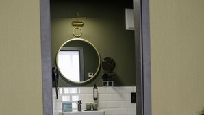A bathroom with a wooden vanity, a round mirror, and a white toilet. - Stadthotel König Albert (Zittau)