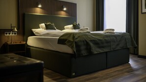 A modern hotel room with a large bed, a bedside table, and a nightstand. - Stadthotel König Albert (Zittau)