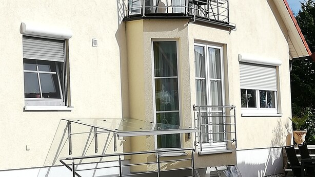 Un bâtiment à deux étages doté d’un balcon, d’un regard d’homme et d’un sol pavé.