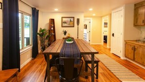 Un coin repas avec une table et des chaises en bois, une plante en pot et un tableau accroché au mur.