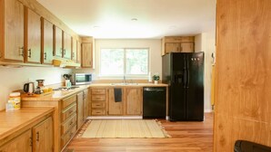 Une cuisine avec des meubles de rangement en bois, un réfrigérateur noir, un four à micro-ondes et un lave-vaisselle.