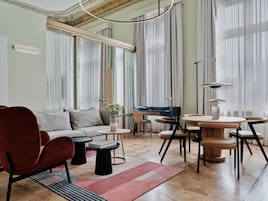 A modern living room with a sofa, chairs, a coffee table, and a dining area with a table and chairs.