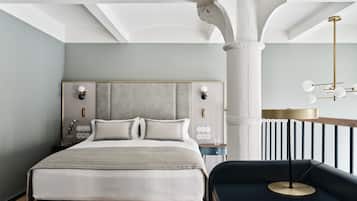 A modern bedroom with a large bed, a nightstand, a reading lamp, and a view of the outdoors.
