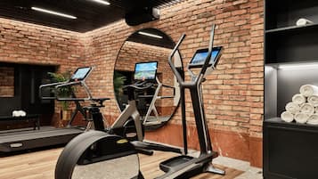 A gym with elliptical machines, a treadmill, and a mirror.