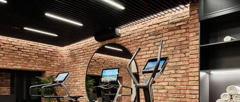 Un gimnasio con elípticas, una cinta de correr y un espejo.