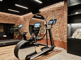 Una palestra con macchine ellittiche, tapis roulant e uno specchio.