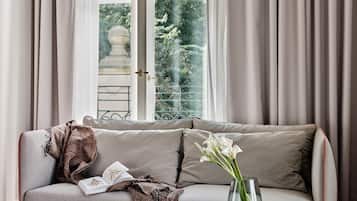 Una sala de estar moderna con un sofá, una mesita redonda y vistas de un jardín a través de un ventanal grande.