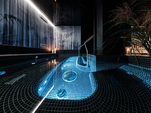 A modern indoor pool with geometric tile patterns, a central water feature, and ambient lighting. - Hotel Altus Palace - Destigo Hotels (Wroclaw)