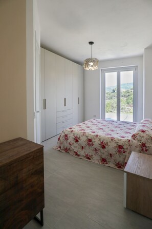Une chambre à coucher comprenant un lit, une armoire, un bureau et un balcon avec vue.