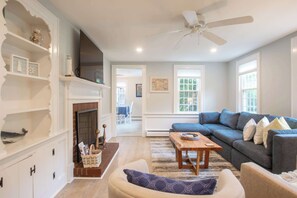A living room with a fireplace, a sofa, a coffee table, and a ceiling fan. - Minutes to Nantucket Sound Beaches! (South Yarmouth)