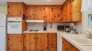 A kitchen with wooden cabinets, a white refrigerator, a microwave, and a sink. - Minutes to Nantucket Sound Beaches! (South Yarmouth)
