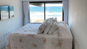Un dormitorio con una cama grande, vistas al mar y un ventilador de techo.