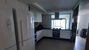Una cocina moderna con armarios blancos, un refrigerador y una ventana que proporciona luz natural.