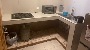 Een kleine keuken met een gasfornuis, een magnetron en een spoelbak.