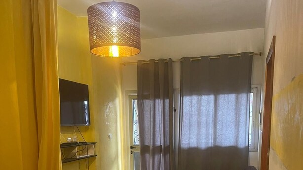 Een kamer met een bed, een aan de muur bevestigde televisie, een bank, een glazen salontafel en een hanglamp.